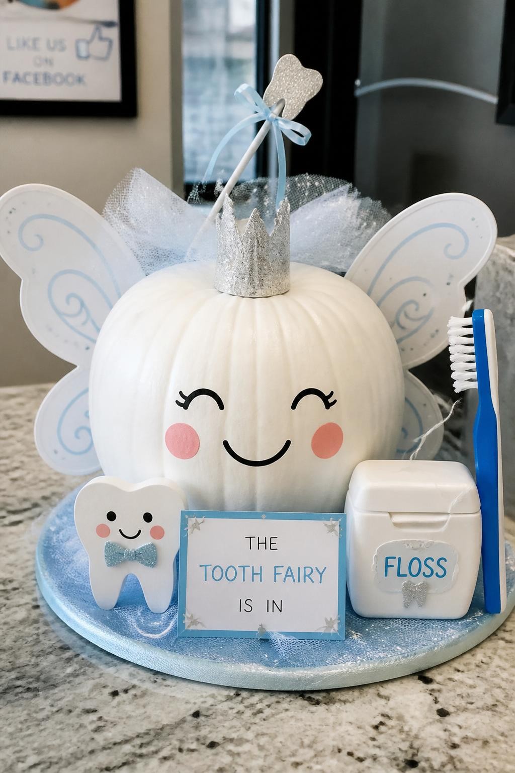 Image Prompt: A realistic DSLR photo of a white pumpkin decorated like a cute dental tooth fairy, with paper wings, tiny crown, smiling tooth cutouts, miniature toothbrush, floss container prop, soft blue and white color palette, clean dental office counter setting, bright natural light, whimsical healthcare contest display.