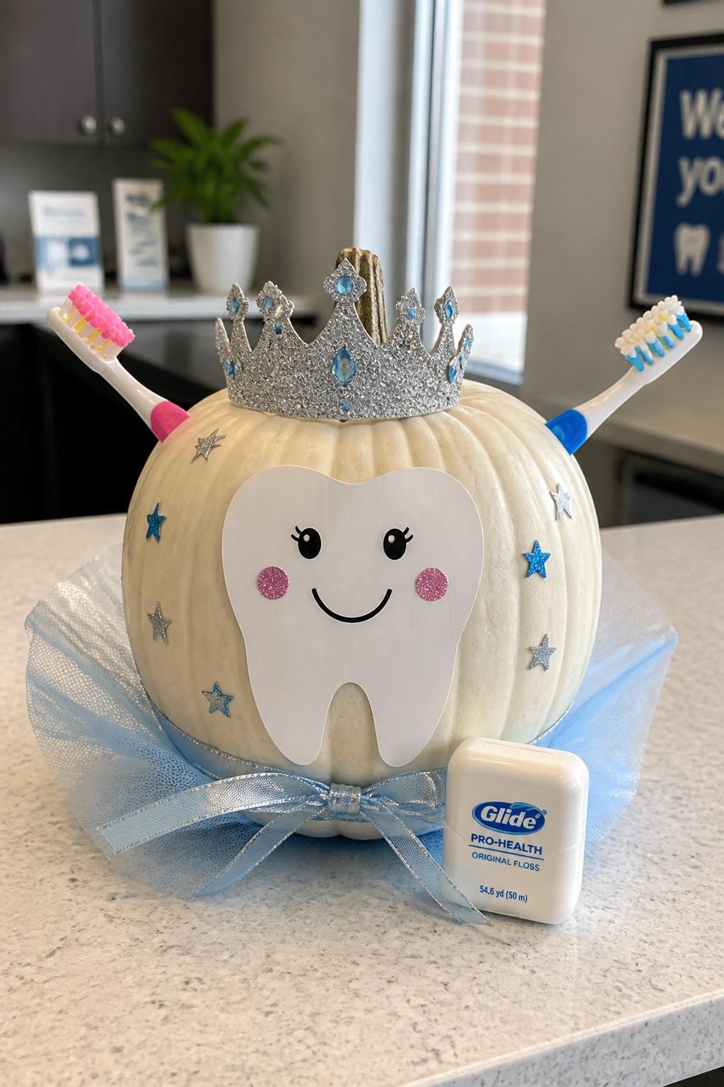 Image Prompt: A realistic DSLR photo of a white pumpkin decorated as a tooth fairy with two colorful toothbrushes crossed behind it like wings, a paper tooth face, silver crown, blue ribbon, floss container prop, and tiny star stickers, displayed on a clean dental clinic counter with bright natural light, playful dental pumpkin decorating idea.