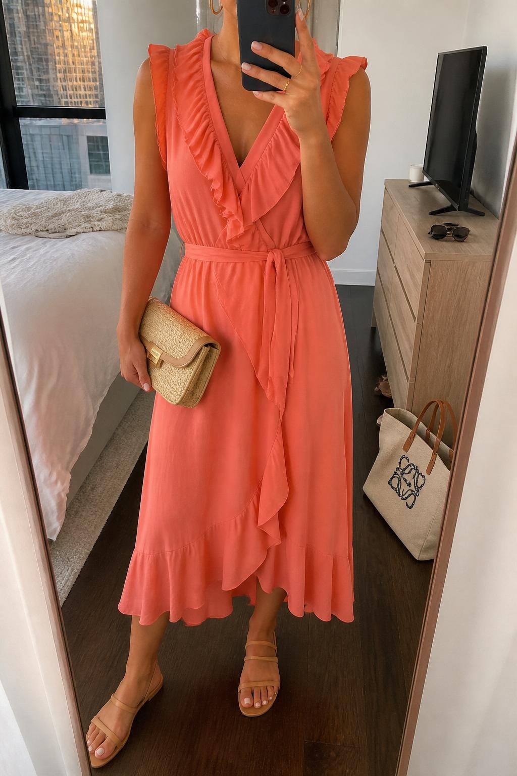 Image prompt
mirror selfie of a woman wearing a coral chiffon midi dress with soft ruffles, nude flat sandals, small gold hoop earrings, and a structured straw clutch, holding a phone in front of a mirror, cropped at NECK so face doesn't show, with a natural casual selfie pose, in a city apartment, evening golden hour, including small lived-in details like a tote bag on the floor, sunglasses on a dresser, or soft bedding in the background, latest iPhone photo quality.