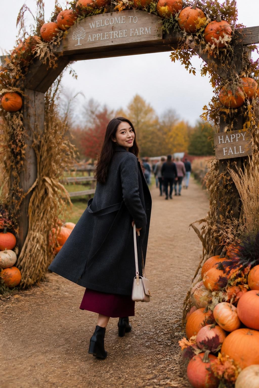 Image Prompt: A realistic full-body photograph of a young East Asian woman walking beneath a farm entrance arch decorated with pumpkins, dried vines, corn husks, and muted fall foliage. She wears a long charcoal coat over a burgundy dress, black ankle boots, and a small cream handbag. Capture her stepping through the arch while looking back over one shoulder, with the coat moving slightly behind her. The arch frames her body without appearing overly symmetrical. Other visitors remain softly blurred in the distance. Soft overcast light, realistic skin and fabric texture, crisp pumpkin details, graceful movement, contemporary fall editorial style.