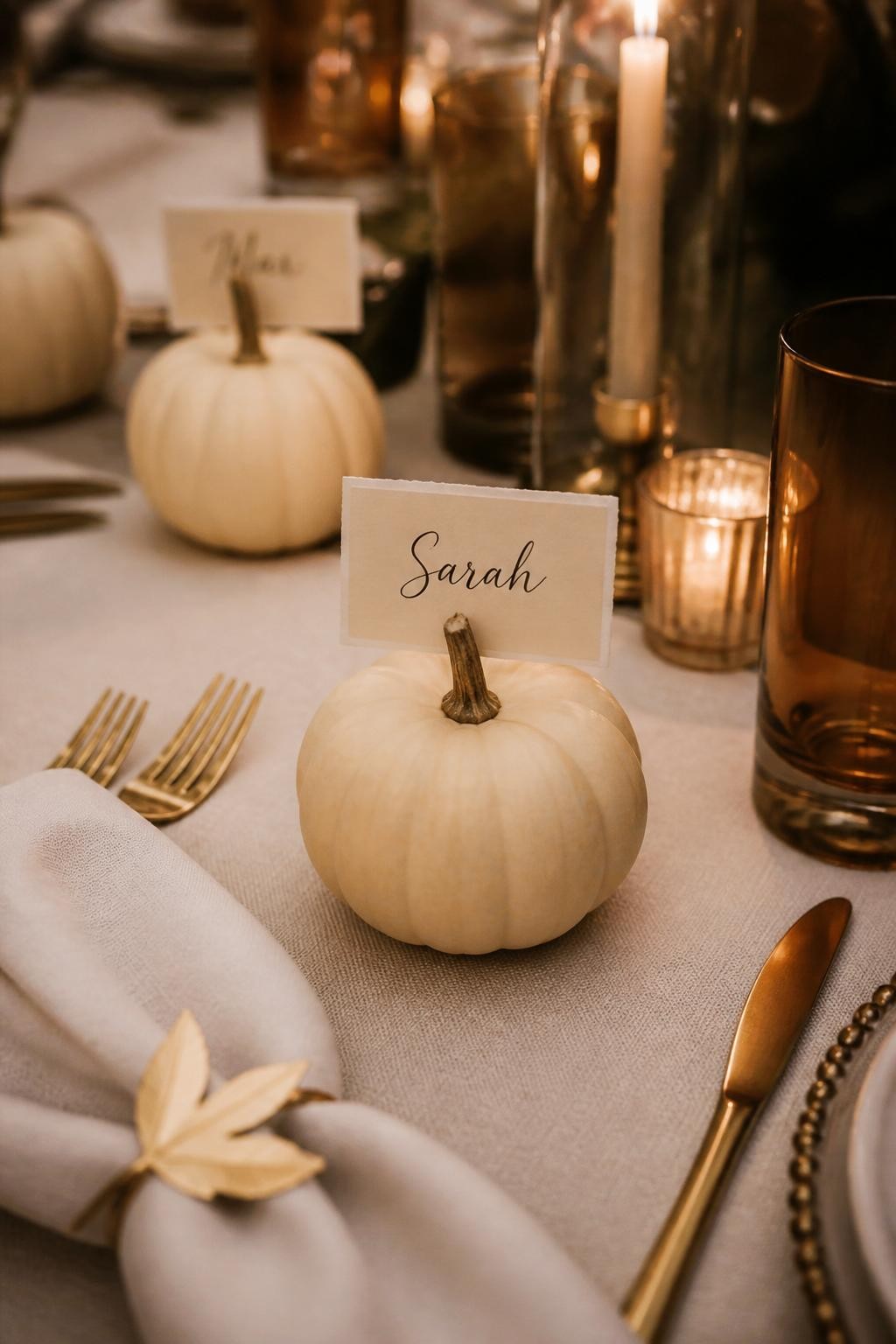 Image Prompt: A realistic DSLR photo of small white pumpkins used as Thanksgiving place card holders, each with a neatly handwritten guest name on a small cream card tucked into the stem, styled on an elegant dinner table with linen napkins, gold flatware, amber glasses, and warm candlelight, polished holiday table setting.